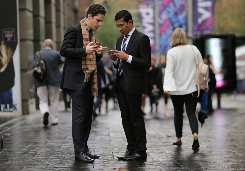 © Reuters.  FILE PHOTO: Businessmen use their phones while standing in the central business district (CBD) of Sydney, Australia, May 14, 2017. Picture taken May 14, 2017. REUTERS/Steven Saphore/file photo